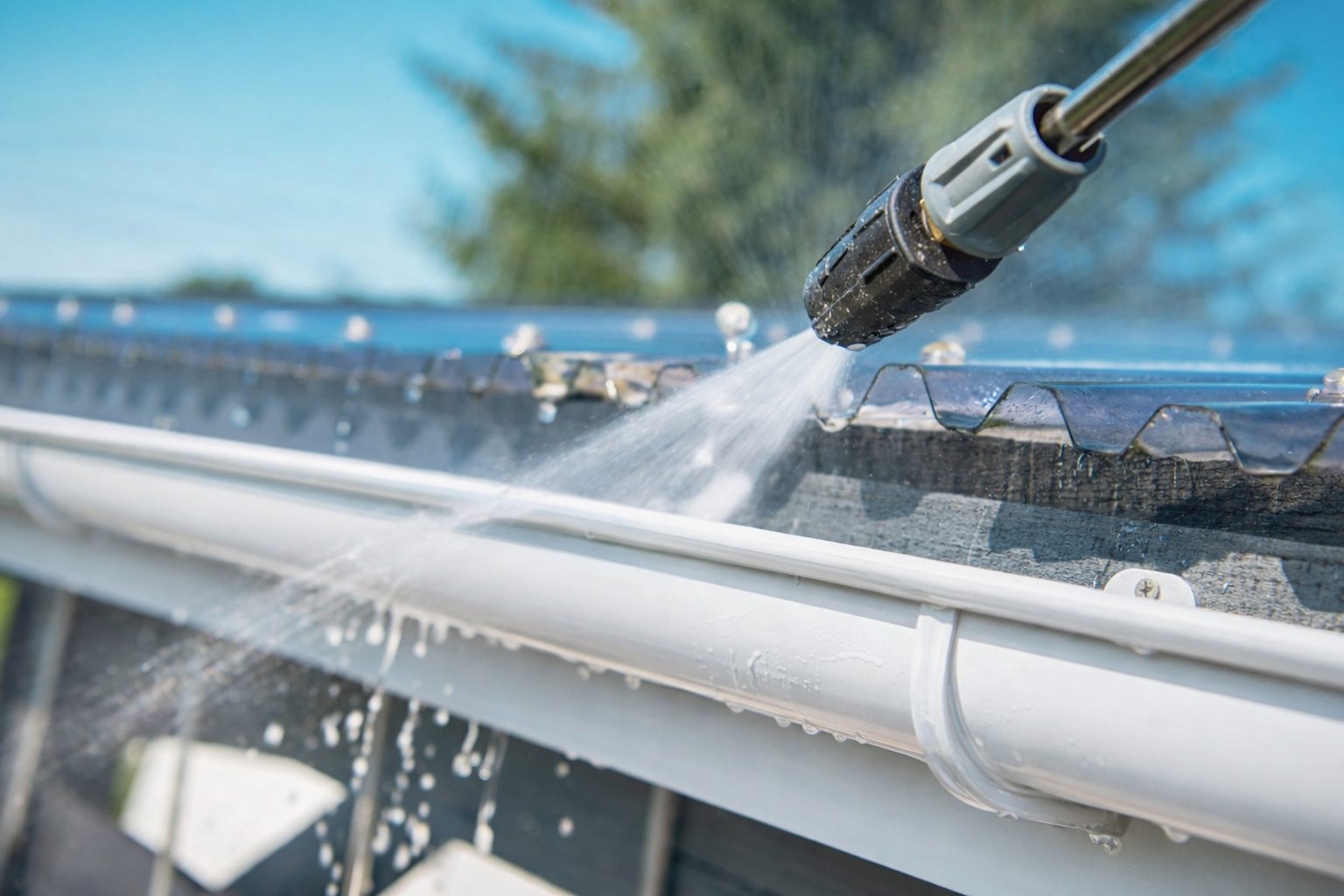 Water spraying from a power washer onto a gutter